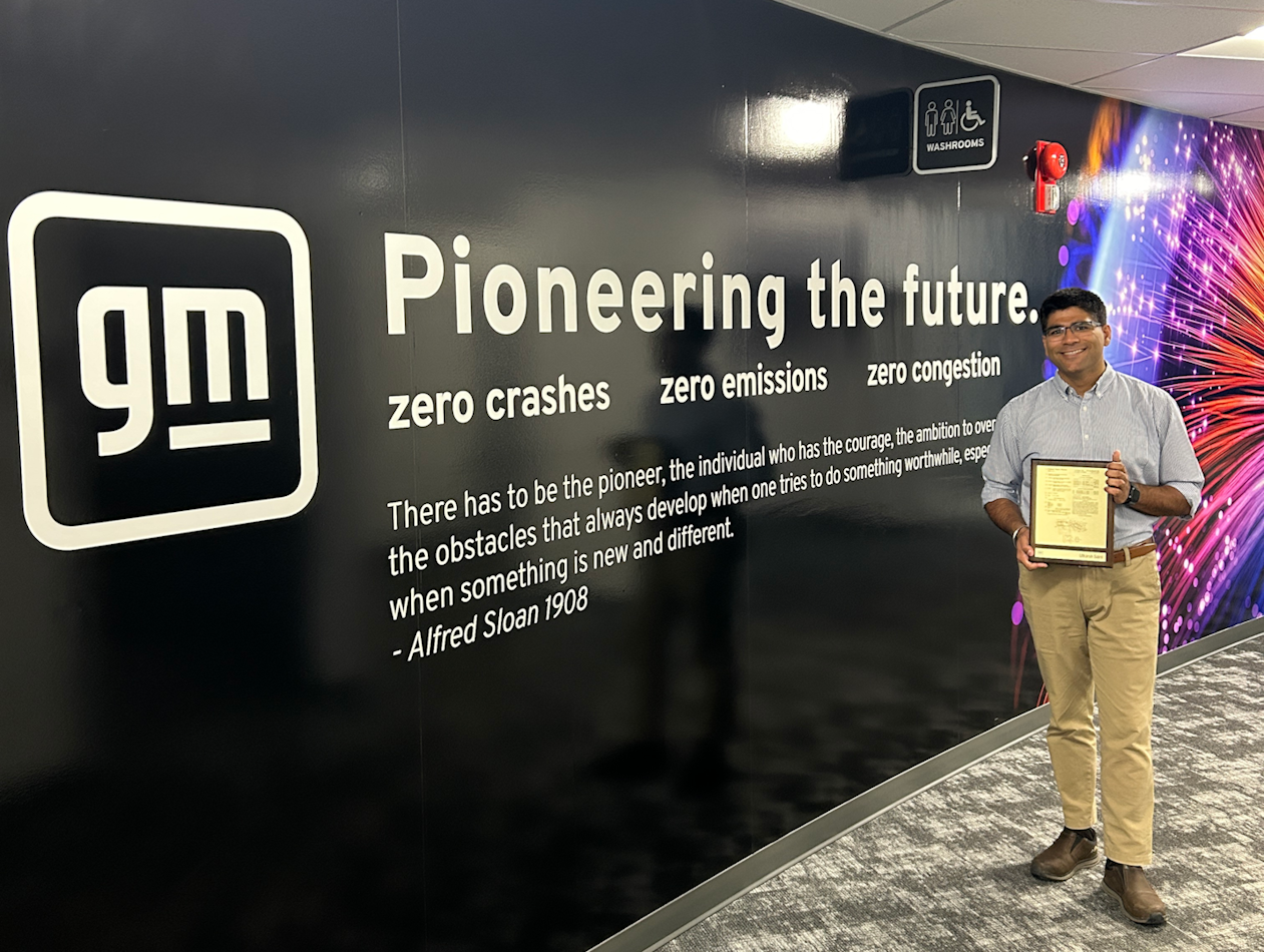 Utkarsh with 1 patent plaque in front of a General Motors backdrop