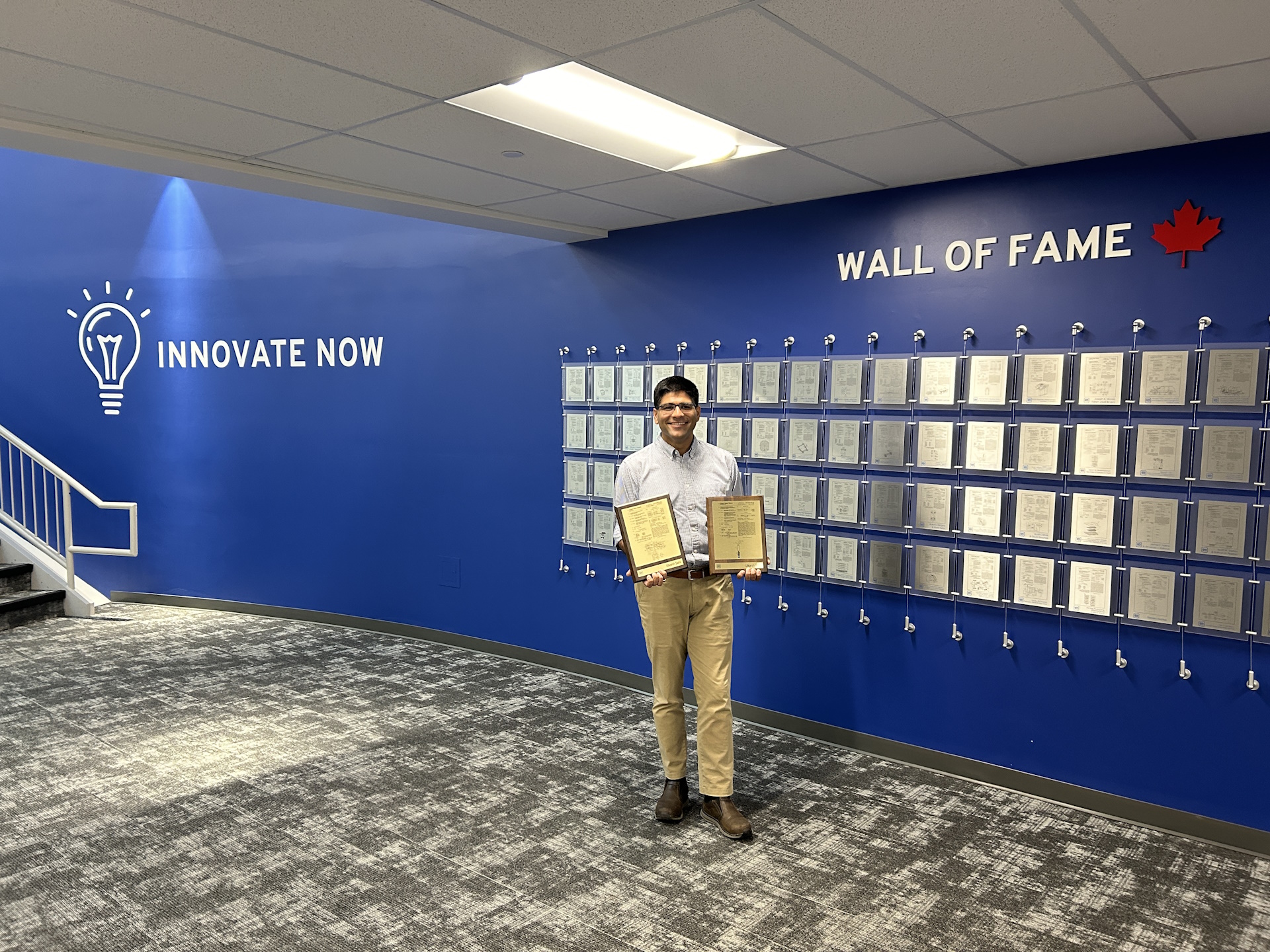 Utkarsh with 2 patent plaques in front of a patent wall